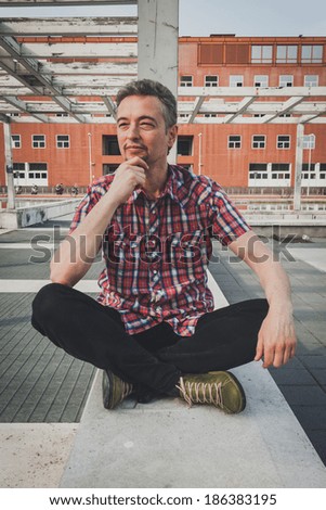 Man in short sleeve shirt sitting outdoor with crossed legs
