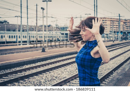 Pretty girl posing along the tracks in a railroad station