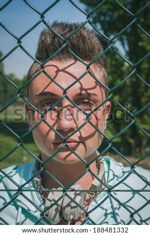 Pretty short hair girl with hoodie behind a metallic net