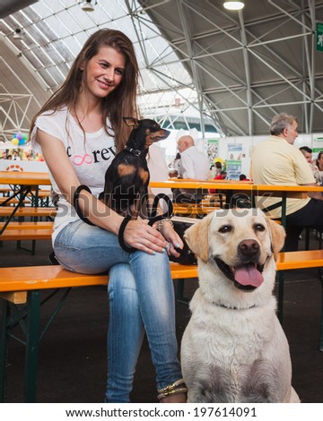 MILAN, ITALY - JUNE 7: Pretty girl poses with her dogs at Quattrozampeinfiera, event and activities dedicated to dogs, cats and their owner on JUNE 7, 2014 in Milan.