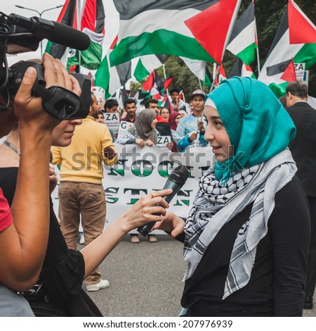 MILAN, ITALY - JULY 26: Young muslim woman talks to tv journalist while protesting against Gaza strip bombing in solidarity with Palestinians on JULY 26, 2014 in Milan.