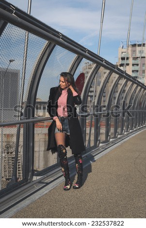 Beautiful young brunette with over the knee boots posing on a bridge