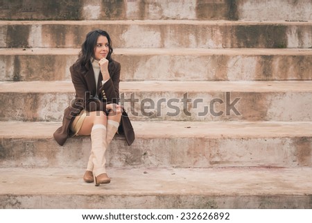 Beautiful young woman with long hair sitting on concrete steps