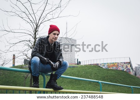 Punk guy with beanie posing in a city park