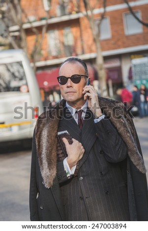 MILAN, ITALY - JANUARY 20: Elegant businessman talking on phone outside Armani fashion show building for Milan Men\'s Fashion Week on JANUARY 20, 2015 in Milan.