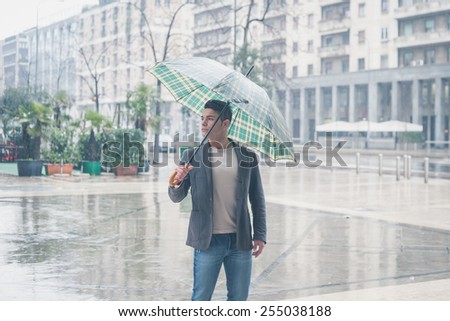 Young handsome man with umbrella posing in the rain
