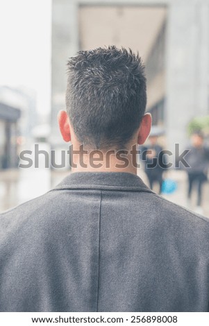Back view of a young handsome man with short hair posing in the city streets