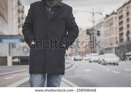 Detail of a young man with coat posing in the city streets