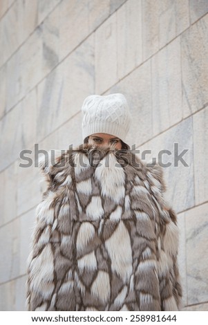 Beautiful young woman wearing ecological fur poses in the city streets - Concept of cruelty free fashion clothing