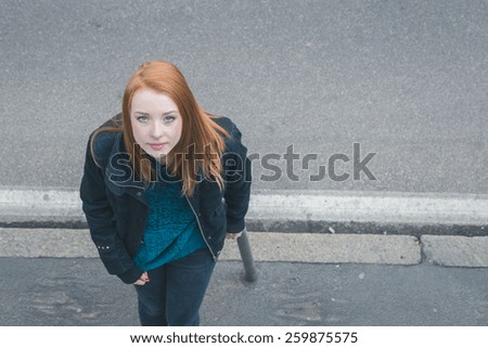 Top view of a beautiful young redhead girl posing in the city streets