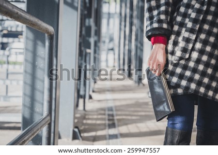 Detail of a young woman with clutch bag posing in the city streets