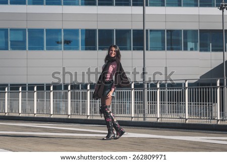 Beautiful young brunette with over the knee boots posing in the city streets