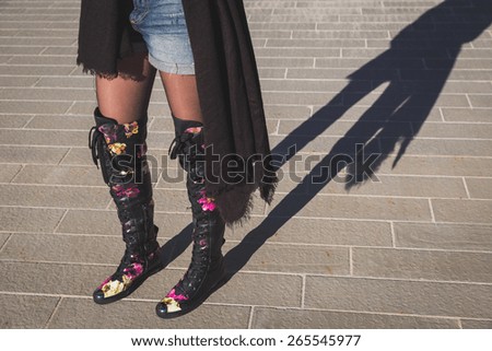 Shadow of a young woman wearing over the knee boots with flowers