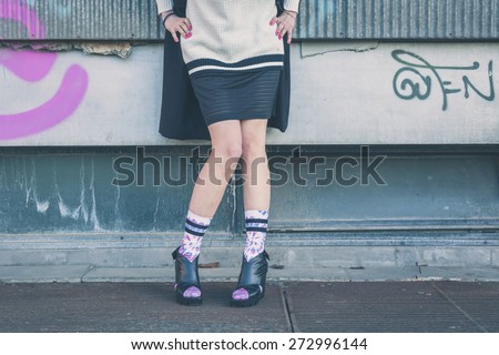 Detail of a young woman wearing wedge heels shoes posing in an urban context