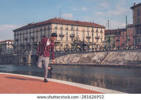 Young handsome Asian model dressed in red blazer posing by an artificial basin