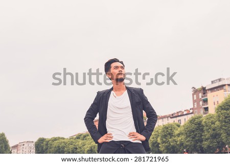 Young handsome Asian model dressed in black posing in the city streets