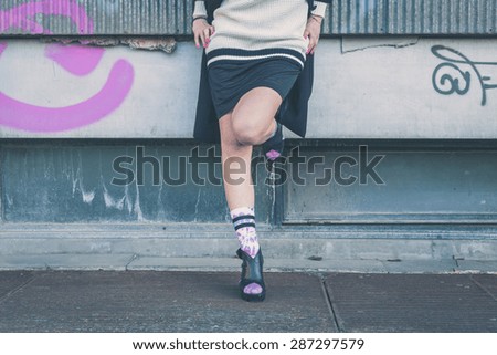 Detail of a young woman wearing wedge heels shoes posing in an urban context