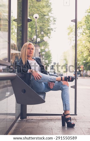 Beautiful blonde girl wearing ripped jeans and leather jacket posing in the city streets