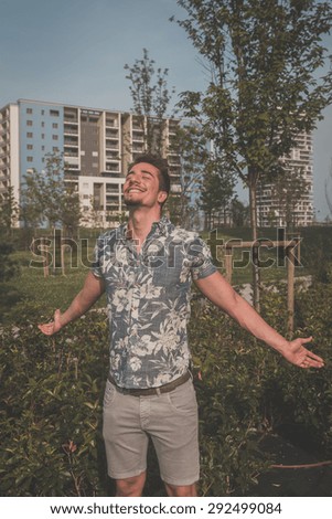 Young handsome man with short hair wearing a short sleeve shirt and posing in an urban context