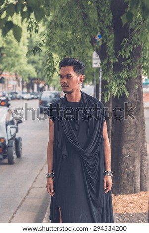 Young handsome Asian model dressed in black tunic posing in the city streets