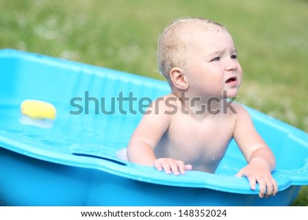 Cute baby sitting in a kiddie pool filled with water