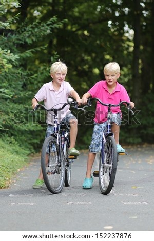Two teenagers boys, twin brothers are cycling in the park