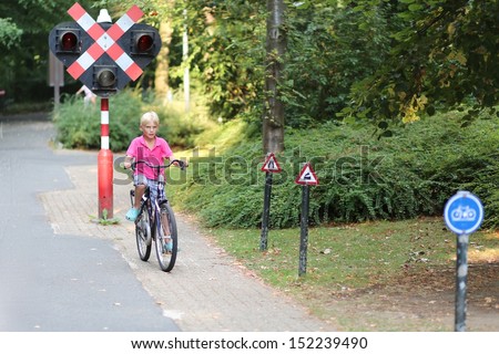 Happy teenager boy cycling on bike at special training playground in the park, he is learning how to drive safely in the city by looking at educational traffic signs