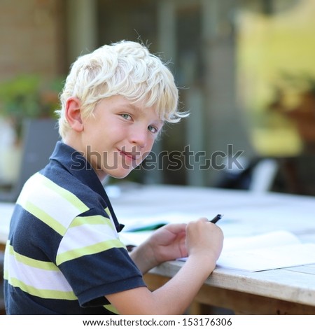 Teenager boy studying home task after school sitting in a garden, he reads and writes