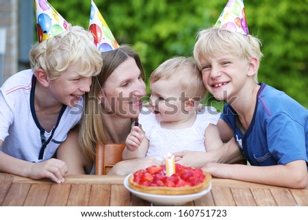 Happy family, mother and three children having fun celebrating first birthday of one year old baby girl