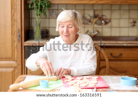 Happy senior woman preparing delicious cookies for her grandchildren