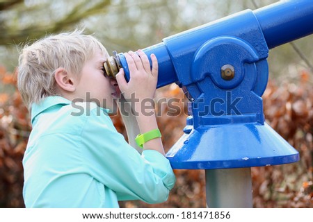 School boy looking through telescope during educational nature discovery project