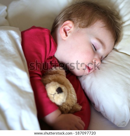 Healthy child, sweetest blonde toddler girl sleeping in bed holding her teddy bear