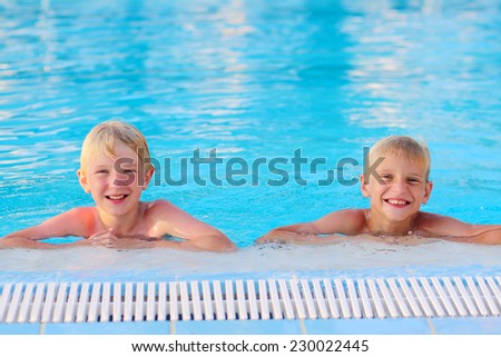 Two happy boys, laughing teenage twin brother, enjoying sunny summer vacation playing in outdoors swimming pool