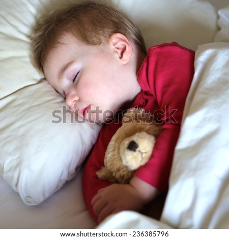 Healthy child, sweetest blonde toddler girl sleeping in bed holding her teddy bear