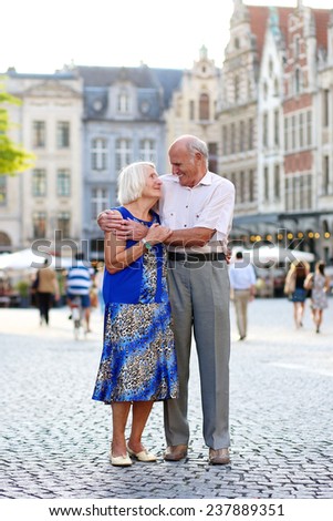 Happy senior couple, man and wife, traveling around Europe, enjoying beautiful old square in city of Leuven, Belgium - active retirement concept