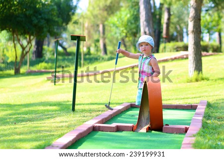 Little active child, two cute toddler girl, playing miniature golf enjoying sunny summer vacation day outdoors in the park