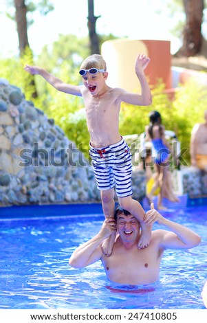 Happy healthy family of two, father and son, laughing teenage boy, having fun together in swimming pool enjoying summer vacation day in aqua park