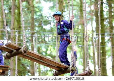 Happy child, healthy teenager school boy enjoying group friends activity in a climbing adventure park on a summer day