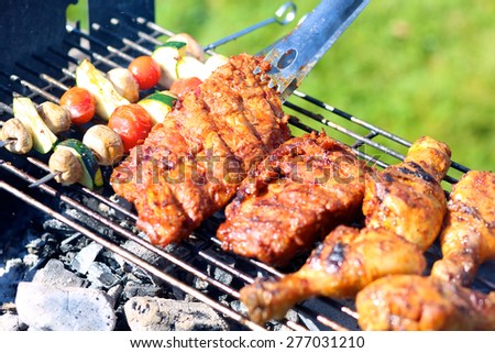 Summertime meal: assorted meat and vegetables on barbecue grill cooked for summer family dinner