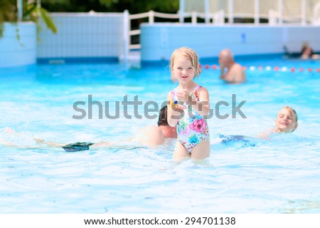 Happy family having fun in recreation swimming pool. Children enjoying day in waterpark during active summer holidays. Kids laughing and playing with waterguns.