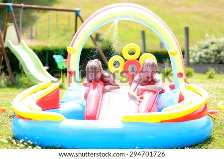 Group of happy healthy kids having fun in inflatable play centre. Children enjoying summer holidays playing in the pool at the backyard in the garden.