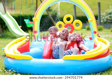 Group of happy healthy kids having fun in inflatable play center. Children enjoying summer holidays playing in the pool at the backyard in the garden.