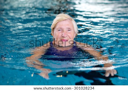 Healthy smiling senior woman swimming in the pool. Happy pensioner enjoying sportive lifestyle. Active retirement concept.