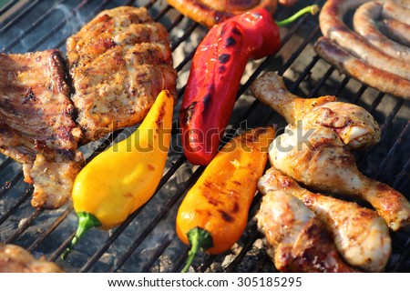 Assorted meat from chicken and pork and colorful sweet paprika on barbecue grill cooked for summer family dinner