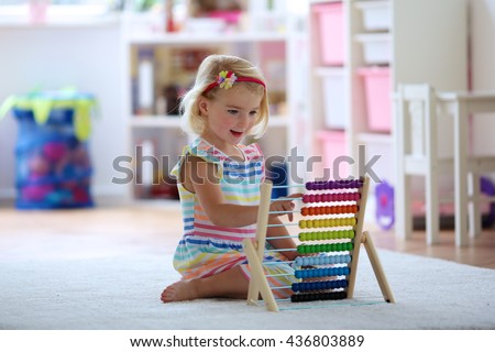 Preschooler girl learns to count. Cute child playing with abacus. Little girl having fun indoors at home, kindergarten or day care centre Educational concept for school kids.
