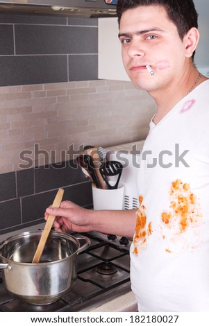 Young man in dirty clothes preparing food and smoking cigarette when wife is away
