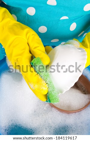 Housewife in apron  washing dishes in kitchen