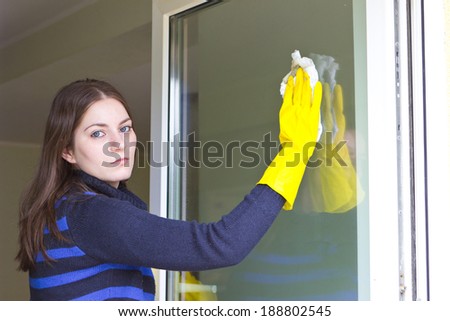 Tired maid with rubber gloves washing windows