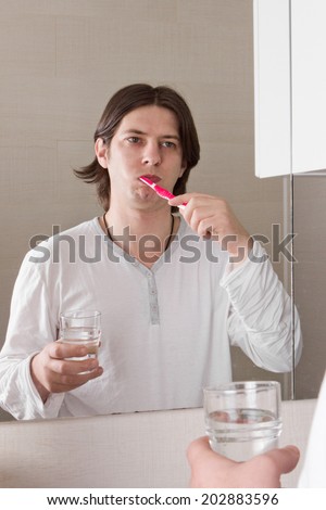 Handsome young man cleaning teeth in bathroom