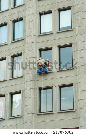 BUDAPEST, HUNGARY - JUNE 29, 2014: Industrial mountaineering worker washing windows of a modern building.